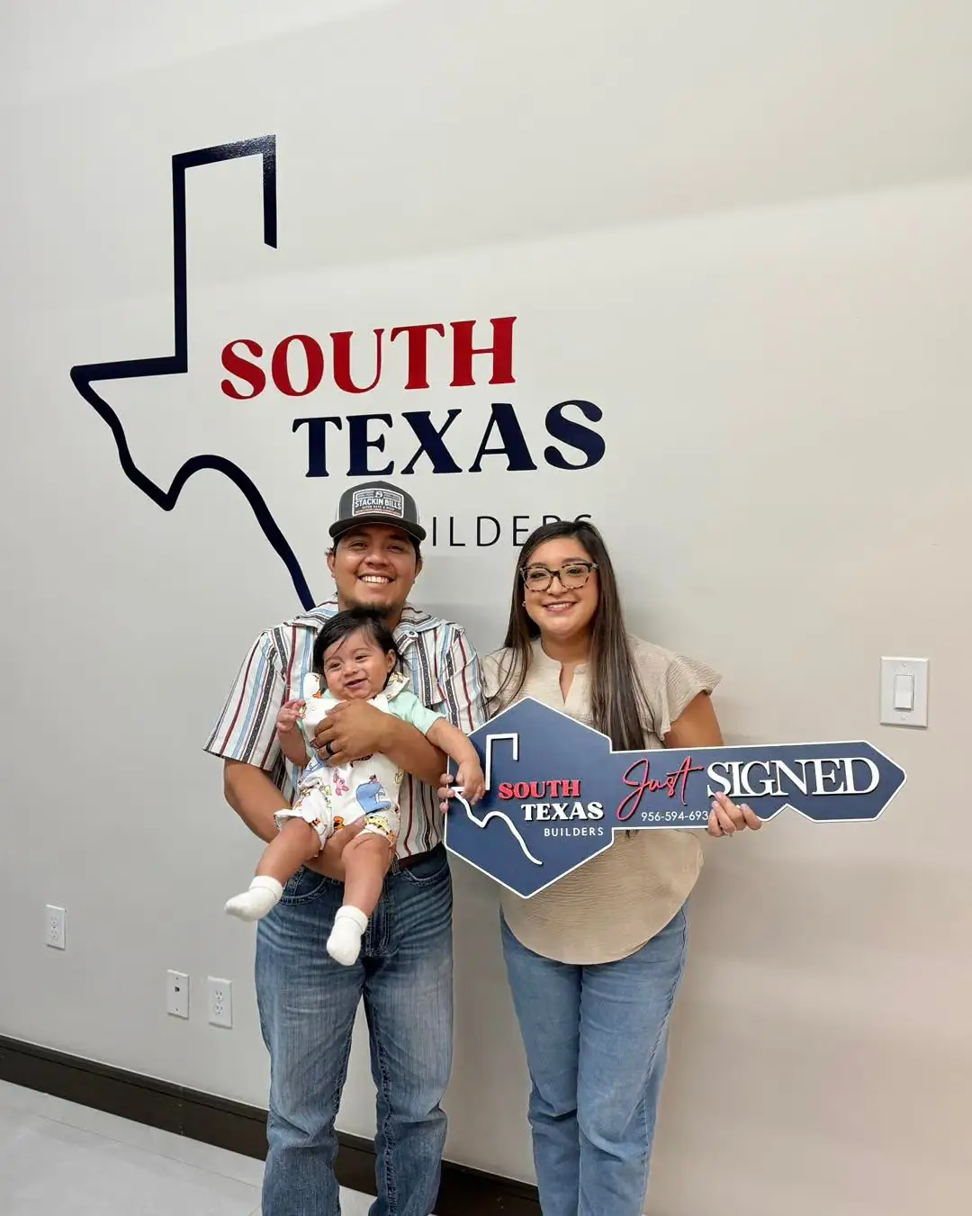 The Tello family with their baby in front of the South Texas Builders wall