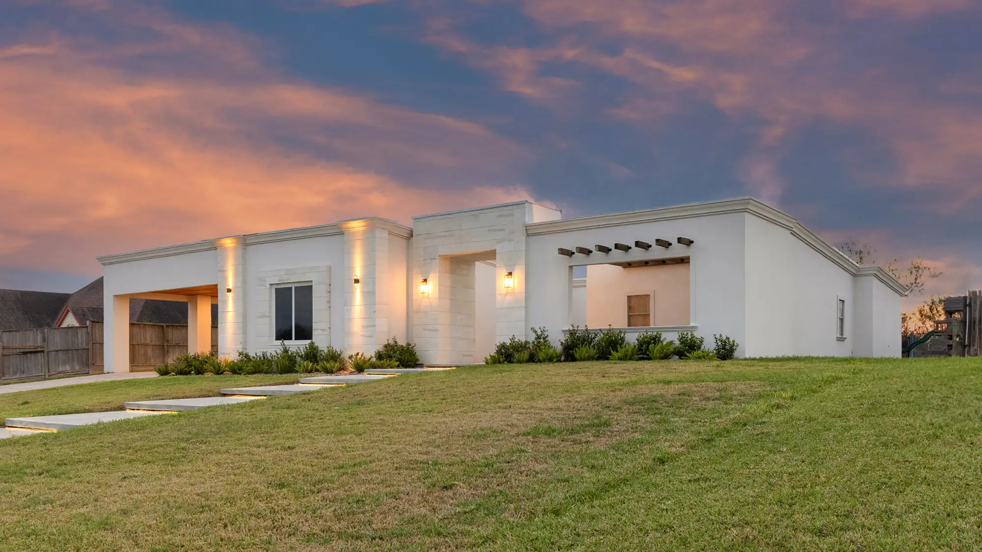 Front massing of the contemporary home with facade uplighting and tall vertical glazing