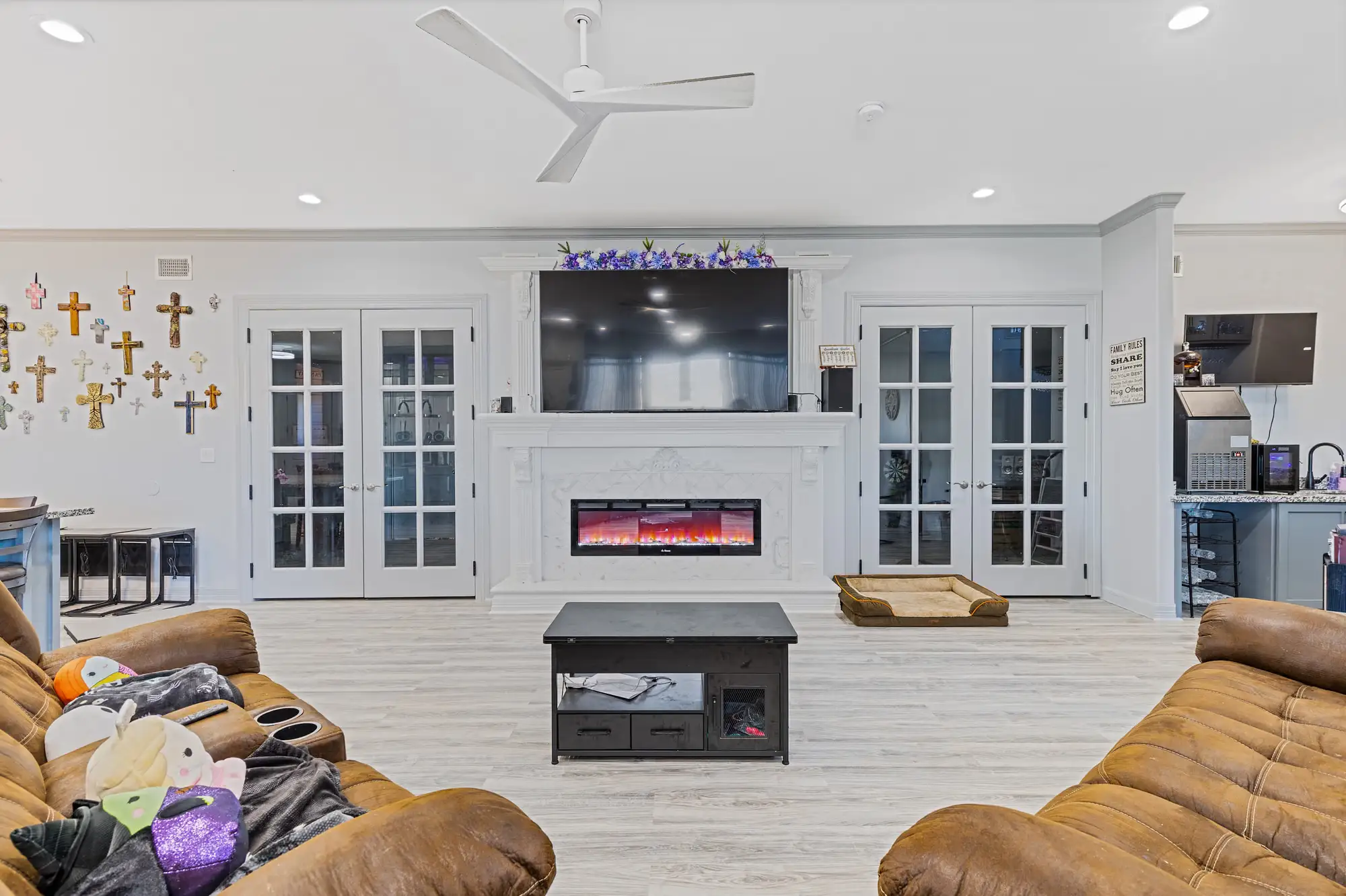 Main living room with an electric fireplace, cross wall and French doors