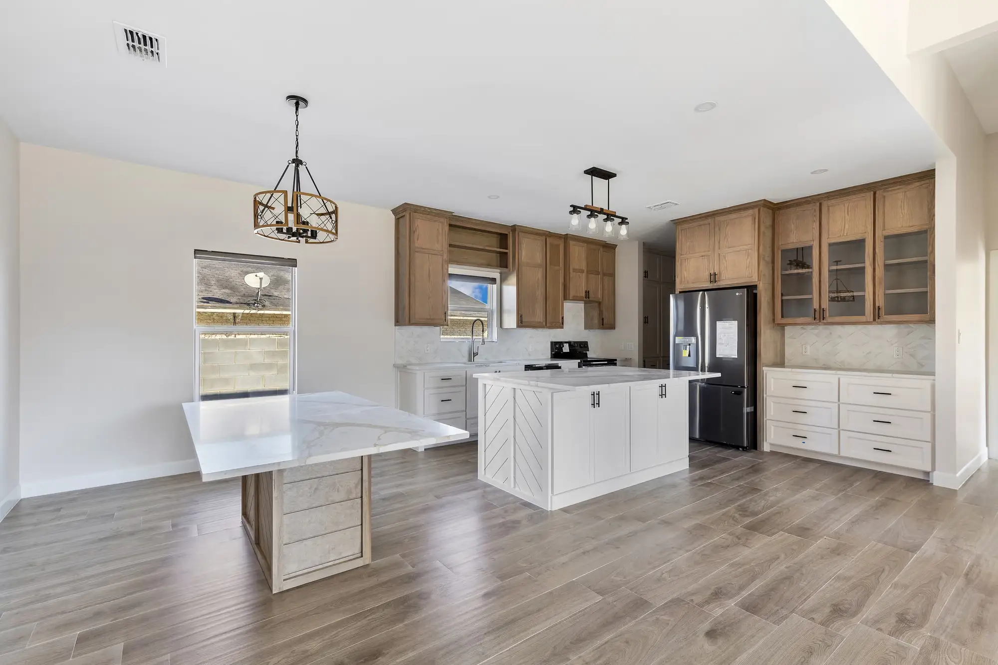 Kitchen with a quartz-topped island, light wood cabinetry and a tall pantry