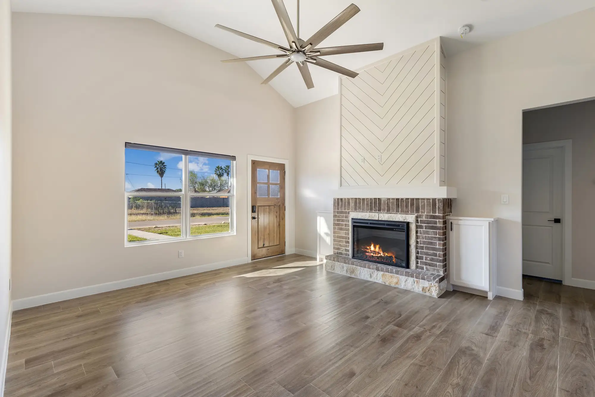 Living room with a vaulted ceiling, brick fireplace and white herringbone wall