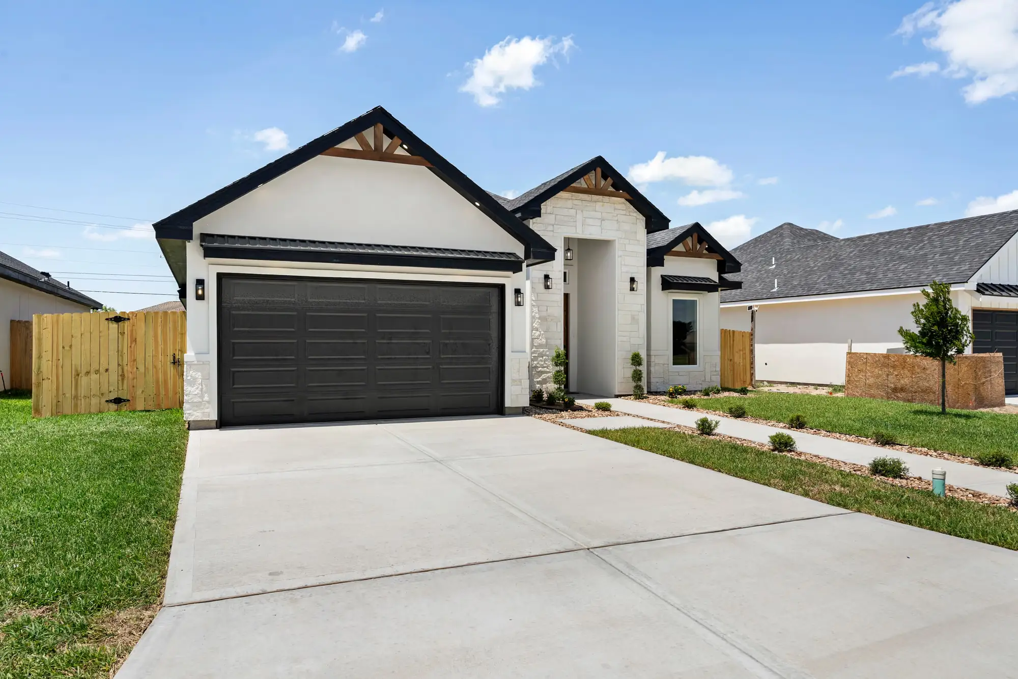 Front elevation in daylight: stone veneer, dark garage door and planted entry bed