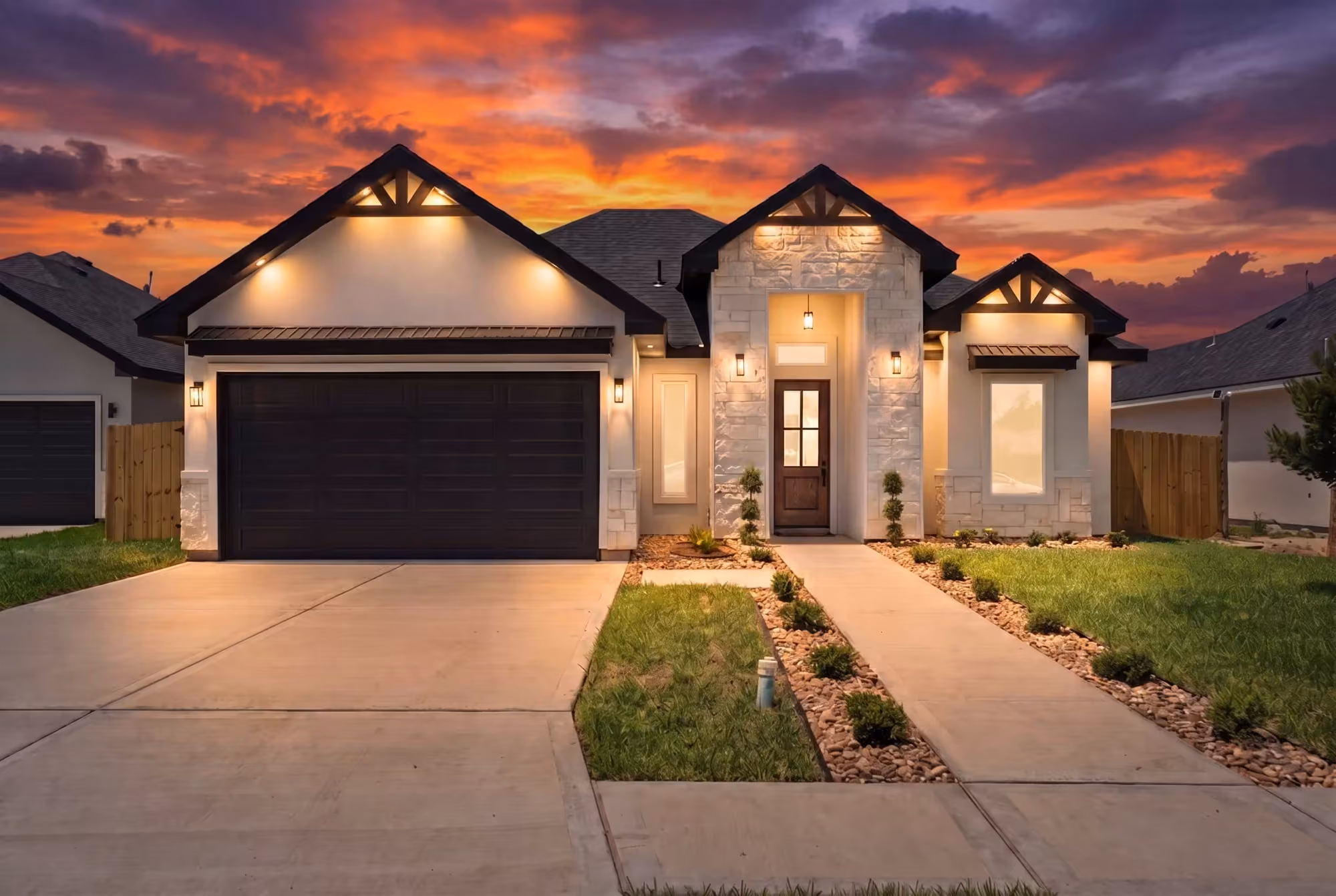 The Laguna Oaks home at dusk, gabled roofline against a lit sky with the entry walk glowing