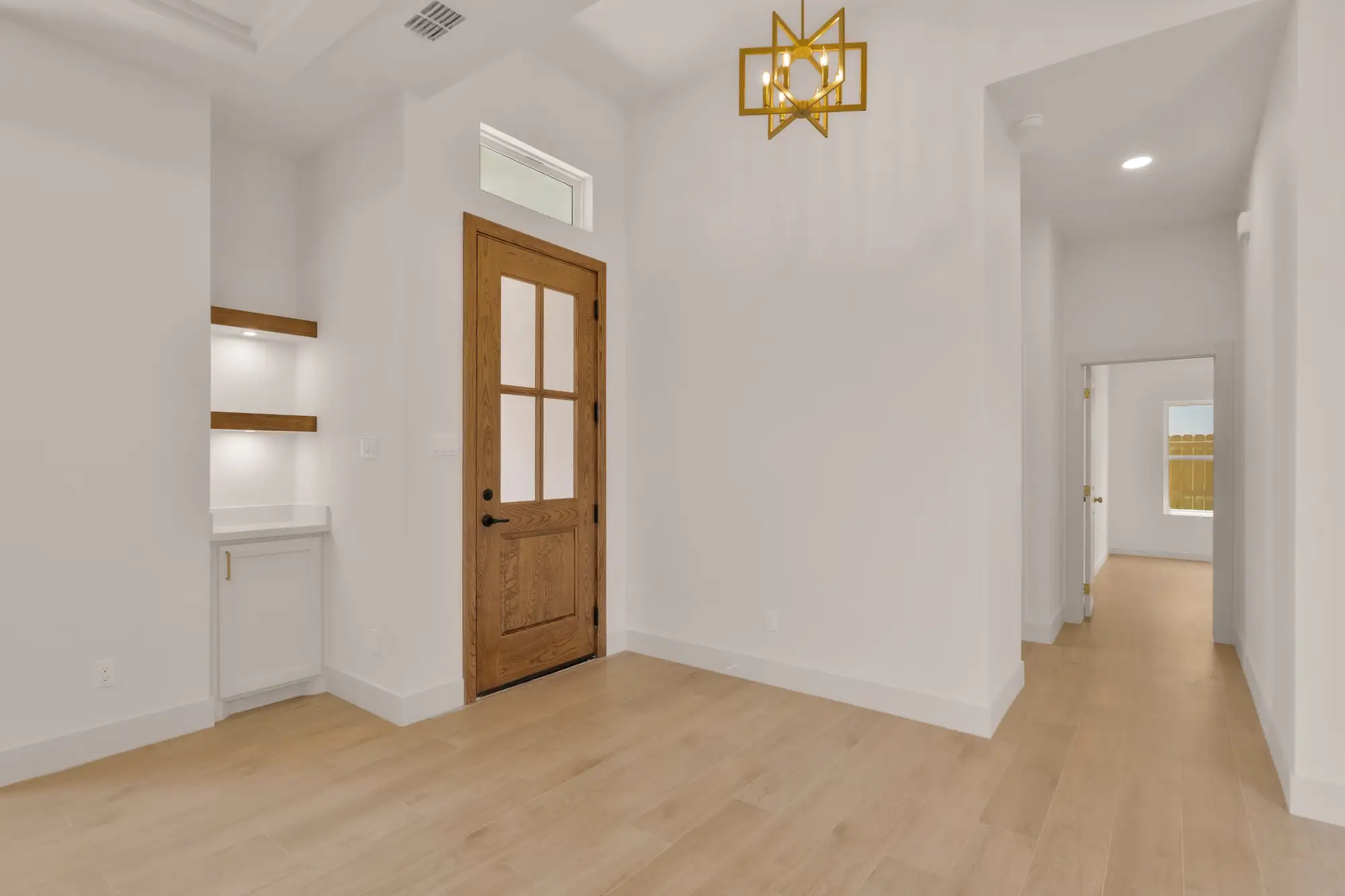 Hallway niche with lit display shelving beside the glass utility door