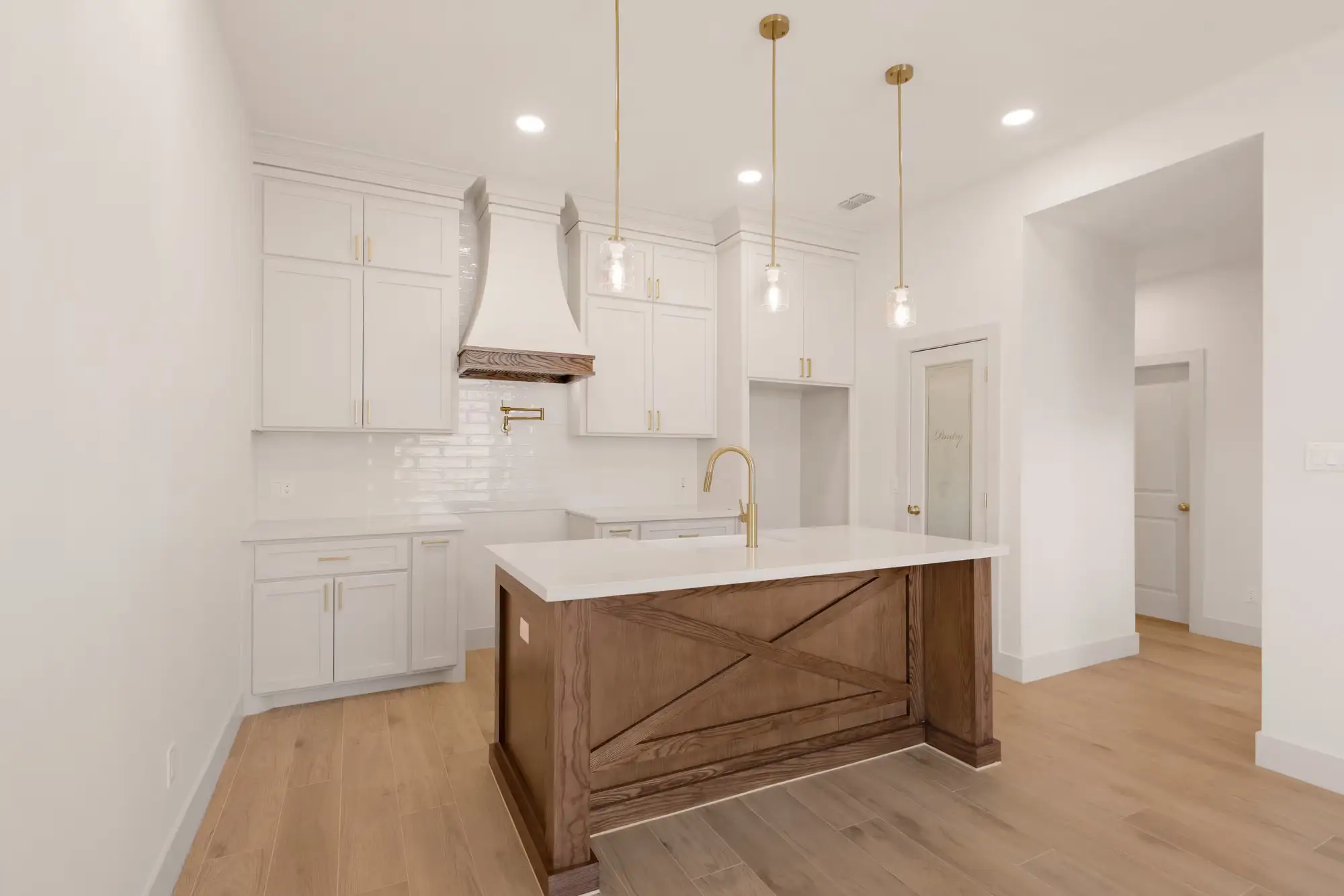 Full kitchen with white quartz counters, farmhouse sink and built-in pantry door