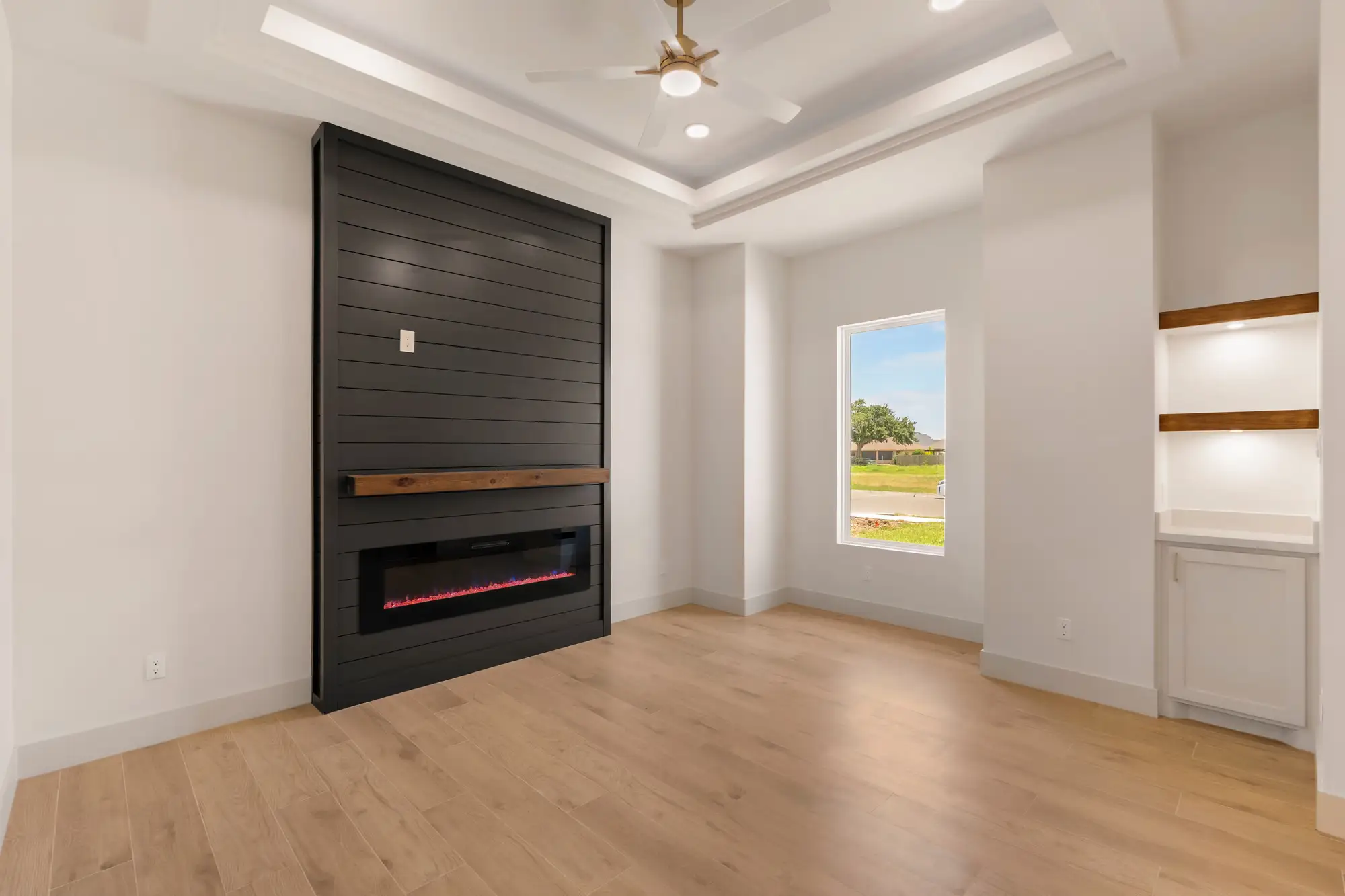 Living room with a linear fireplace set into a dark slat wall and floating shelves