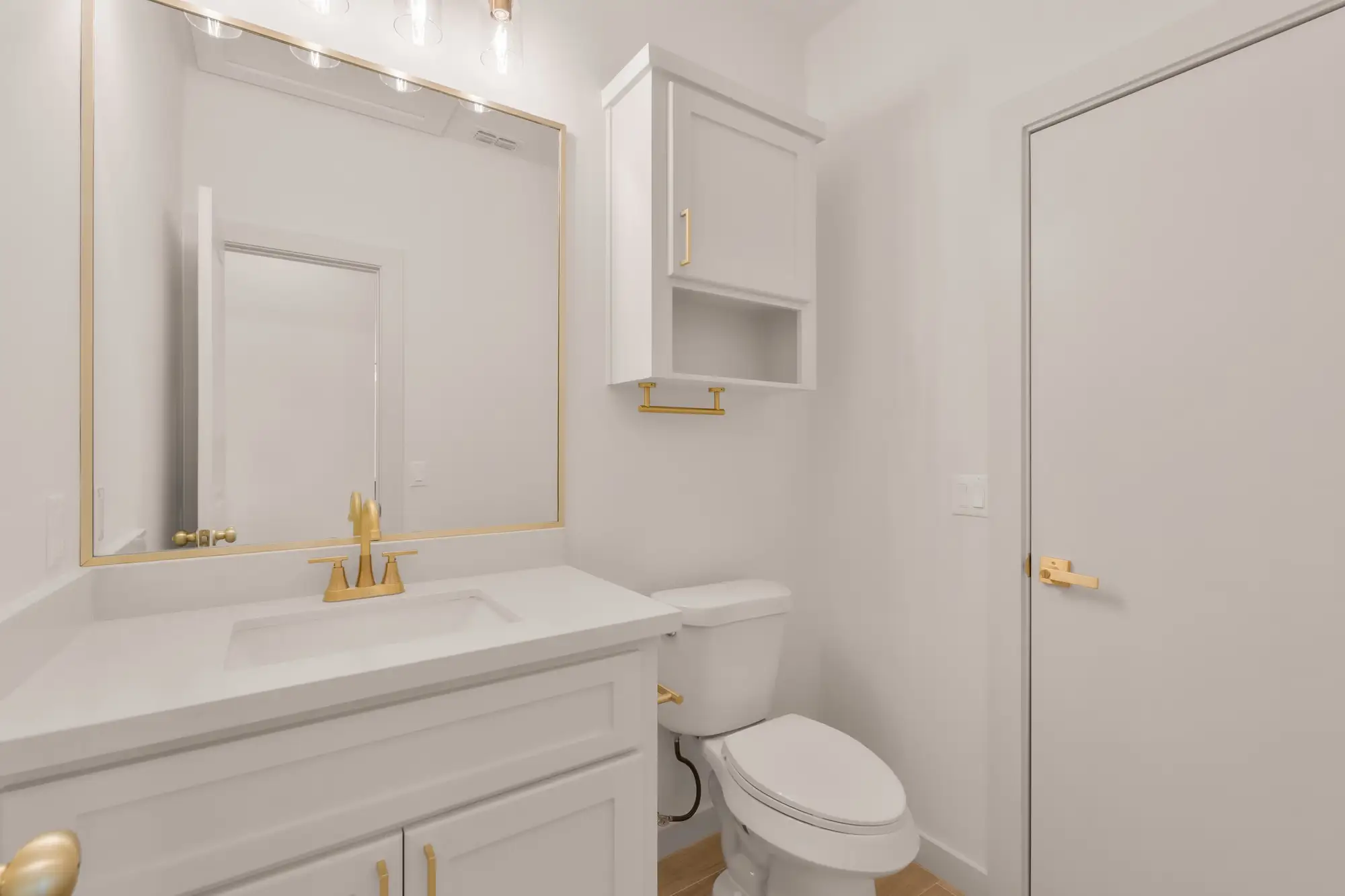 Powder room with a brass-framed mirror over a quartz-topped vanity