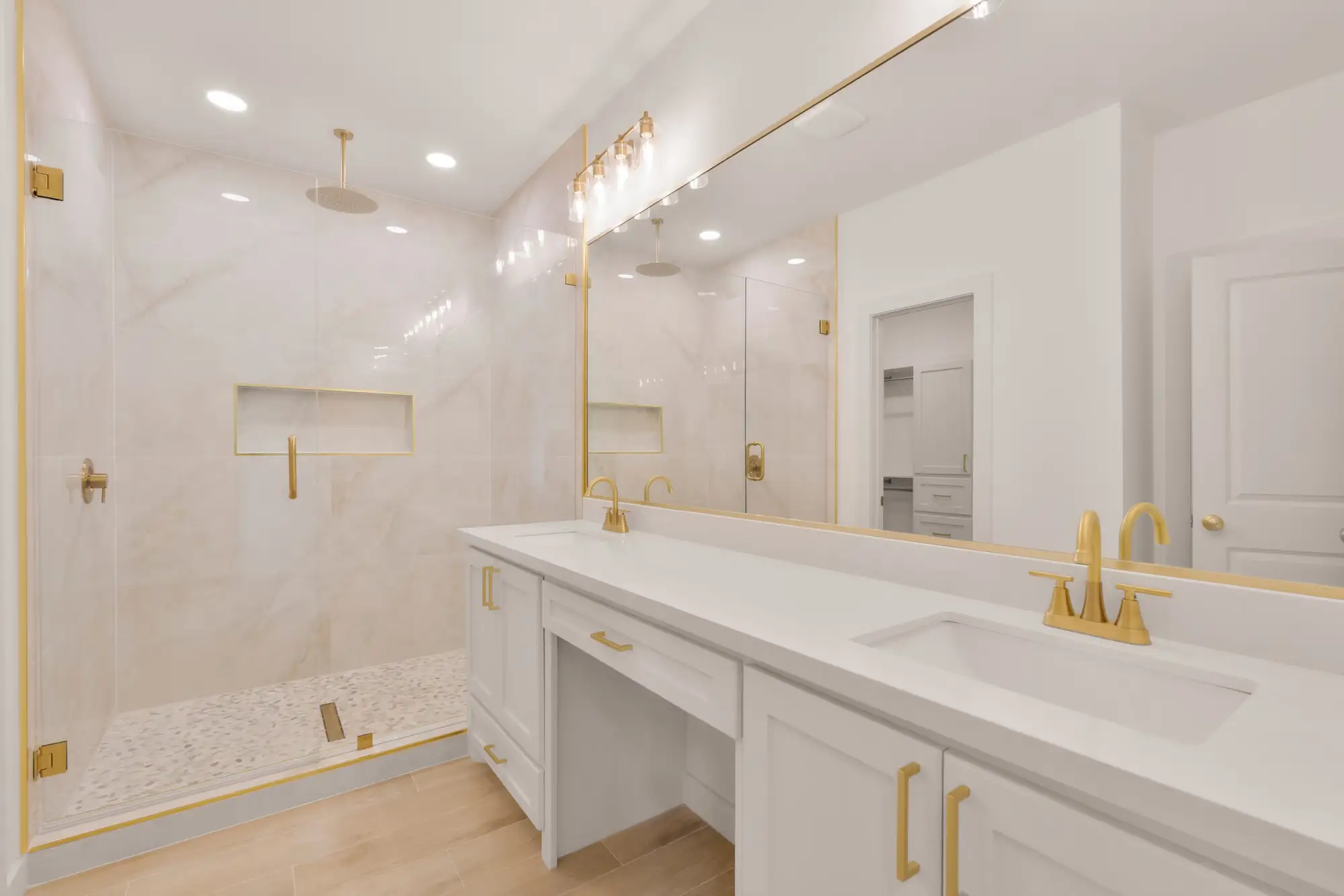Primary bath with a double vanity, center makeup counter and brushed brass fixtures