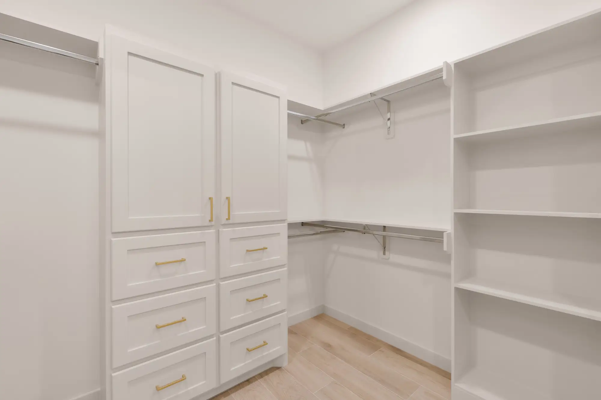 Walk-in closet with a center drawer bank, open shelving and double hanging rods