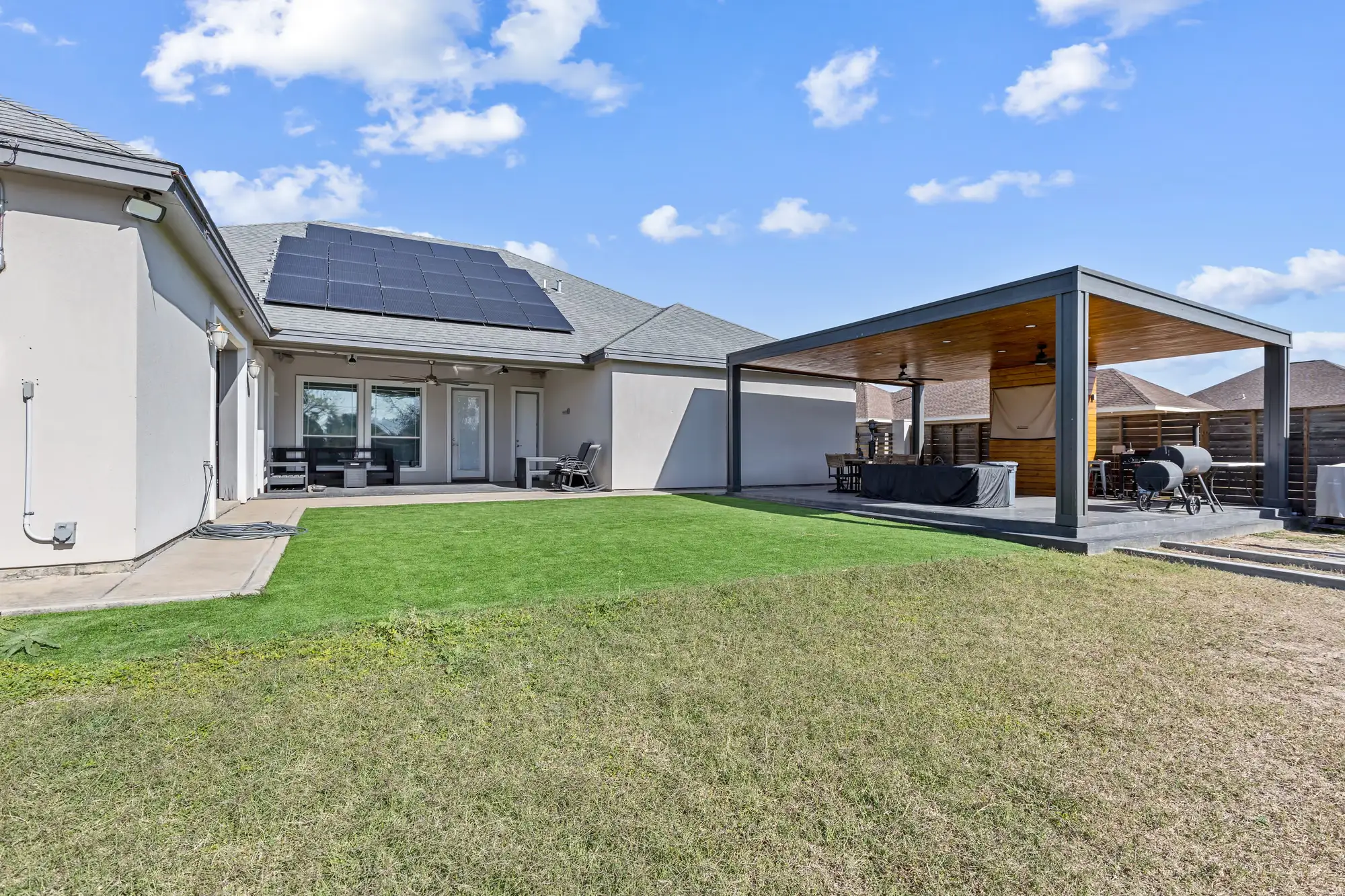Flat-roof outdoor pavilion with a covered lounge facing the back yard