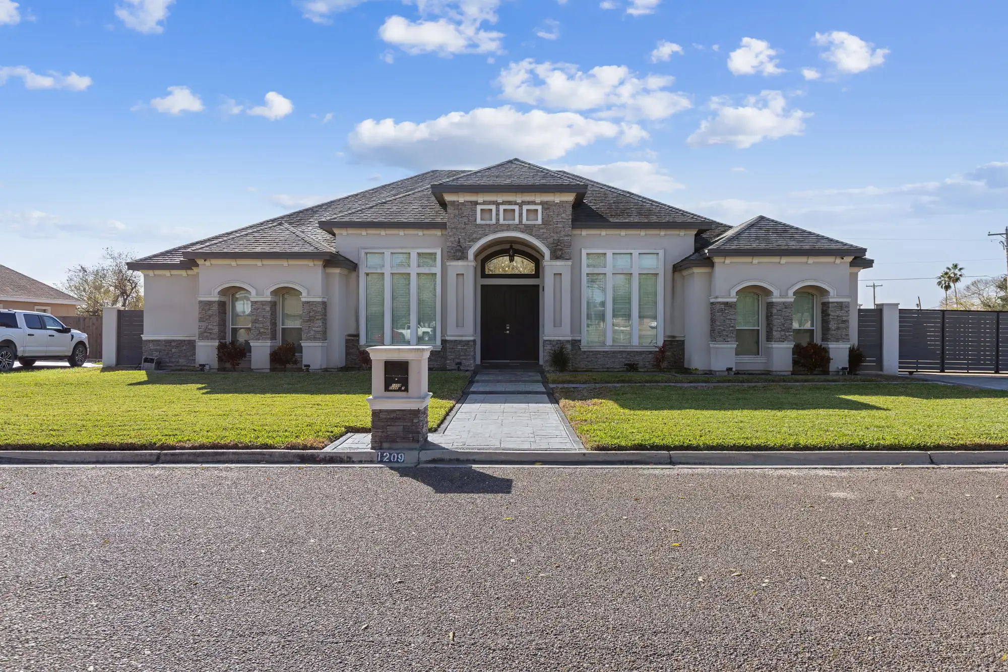 Transitional elevation with an arched entry, stucco banding and finished front landscaping