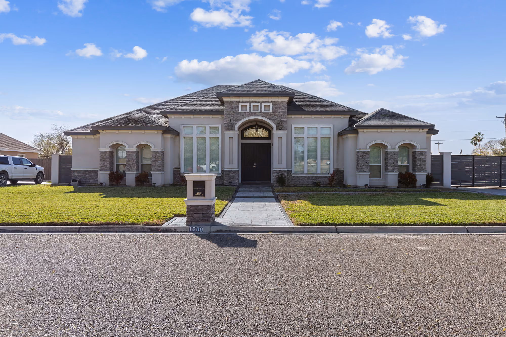 Transitional elevation with an arched entry, stucco banding and finished front landscaping