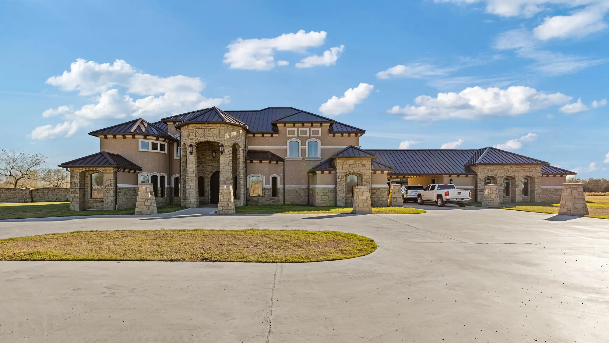 Mediterranean-inspired elevation with an arched entry tower, clay tile roof and stone base