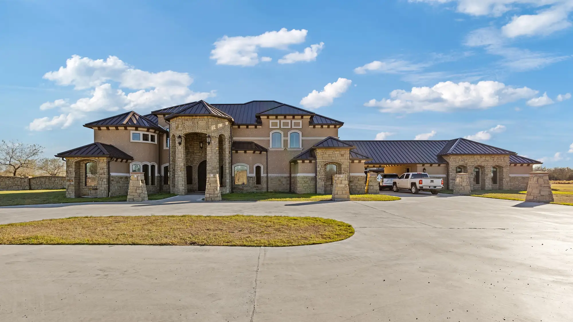 Mediterranean-inspired elevation with an arched entry tower, clay tile roof and stone base