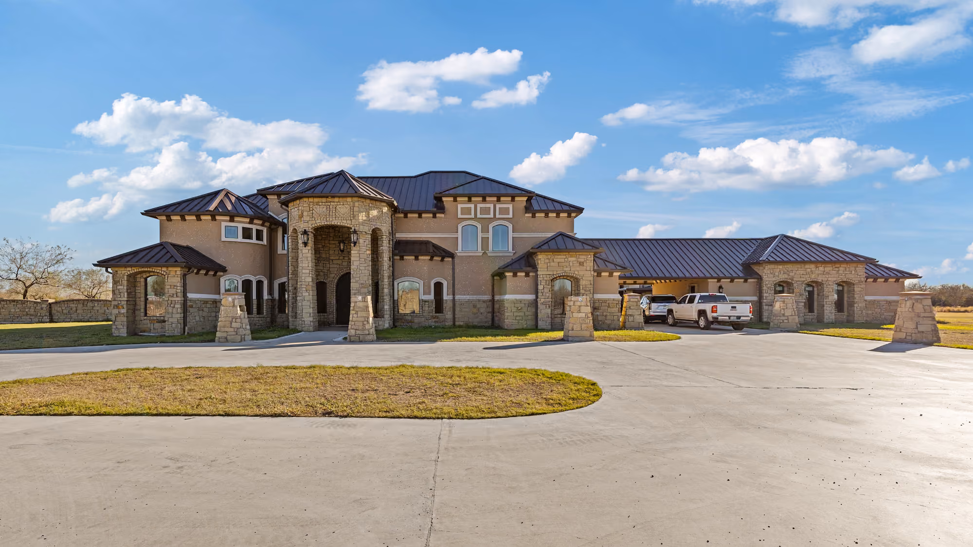 Mediterranean-inspired elevation with an arched entry tower, clay tile roof and stone base