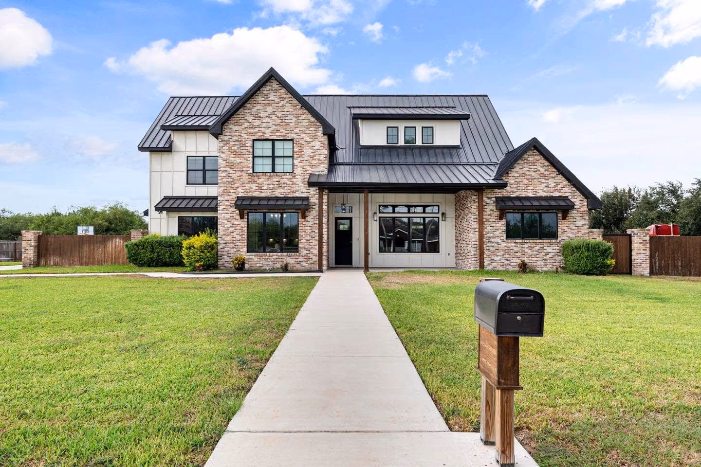 Two-story elevation in mixed brick under a standing-seam gable, with a center walk to the door