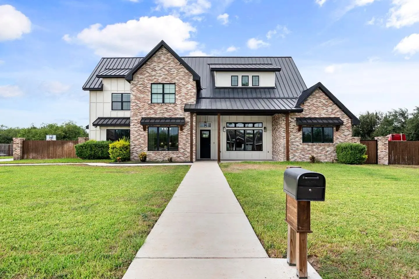 Two-story elevation in mixed brick under a standing-seam gable, with a center walk to the door