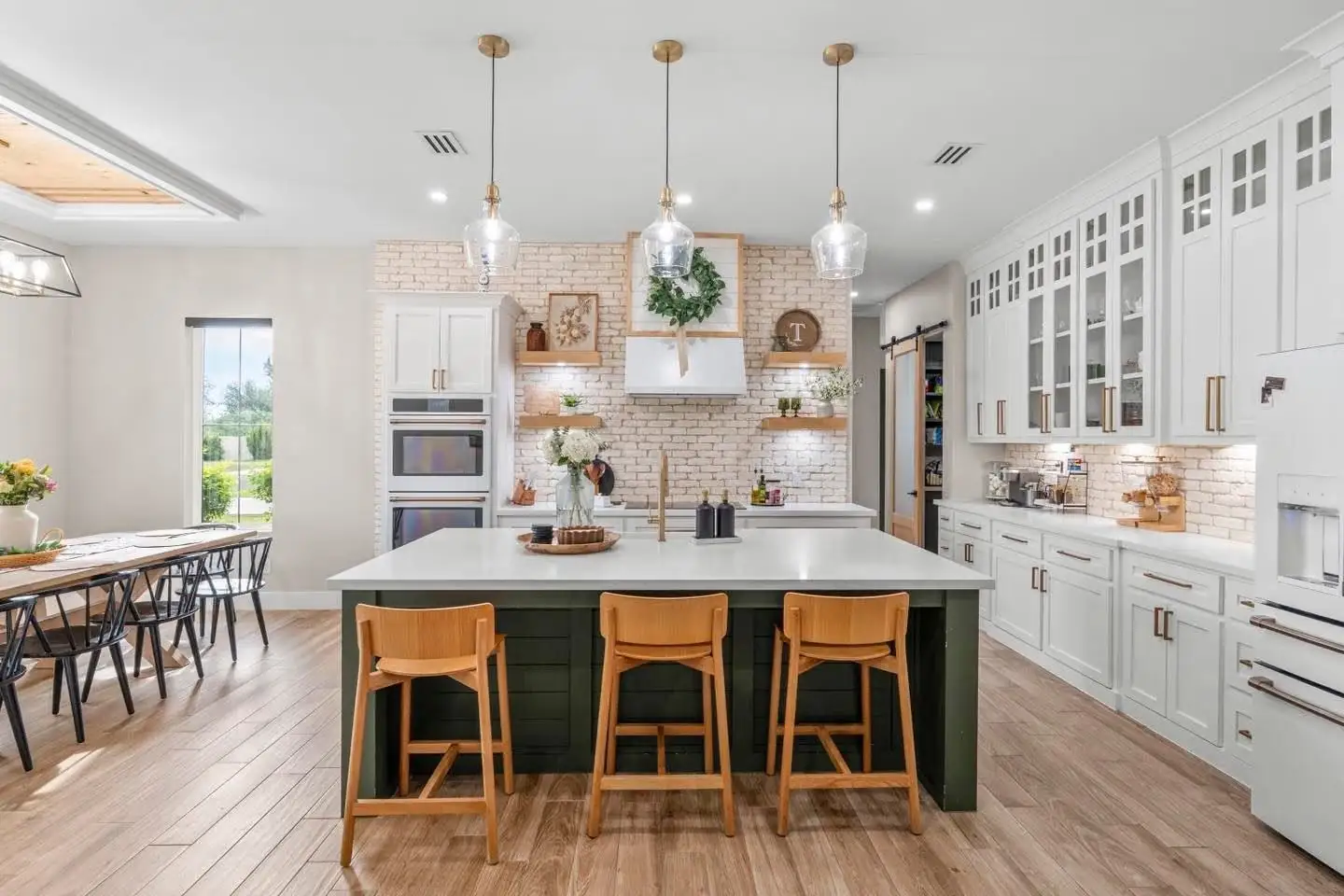 Kitchen with a forest-green island, wood counter stools and a window over the sink