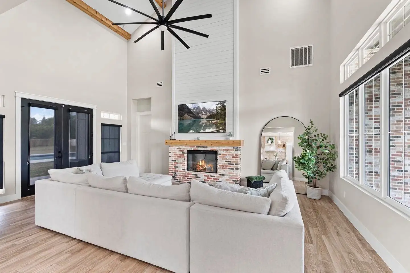 Living room with a brick fireplace, vaulted ceiling and French doors to the patio