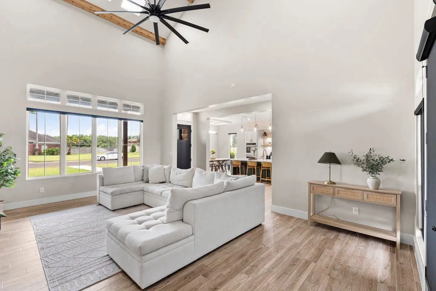 Vaulted living room with a long-blade fan and an open pass to the kitchen