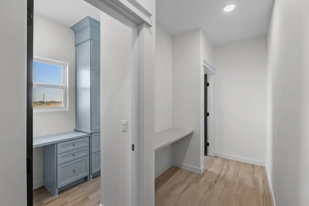 Built-in desk nook with blue drawer bank and a window to the yard