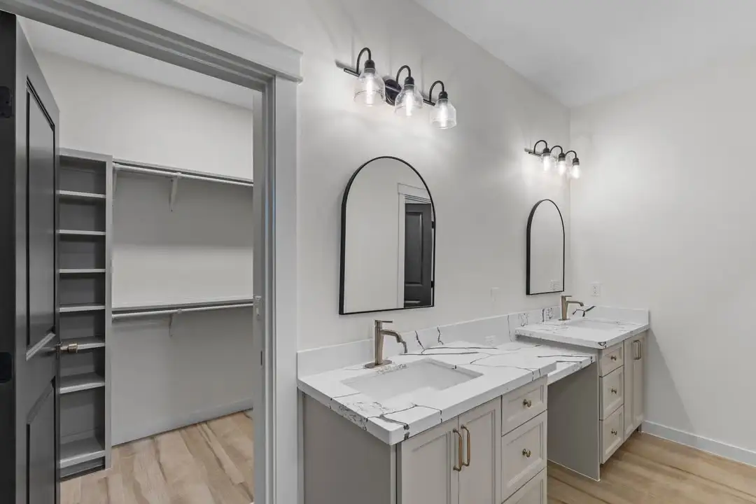 Bath with paired arched mirrors, wall sconces and a marble counter