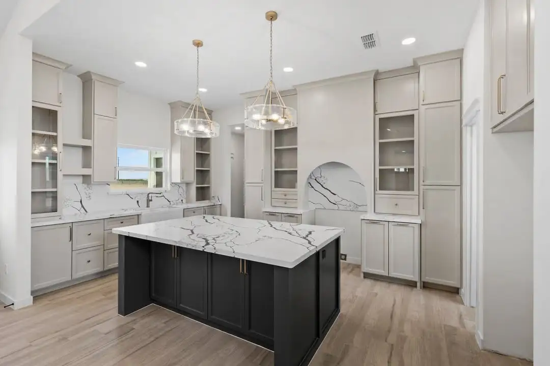 Full kitchen view with the dark island, glass uppers and masonry arch