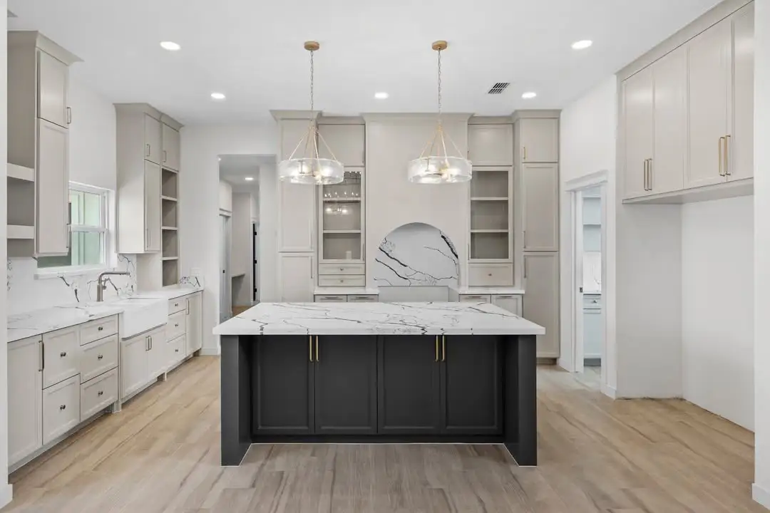 Kitchen with a dark island base, glass display cabinets and a masonry arch over the range