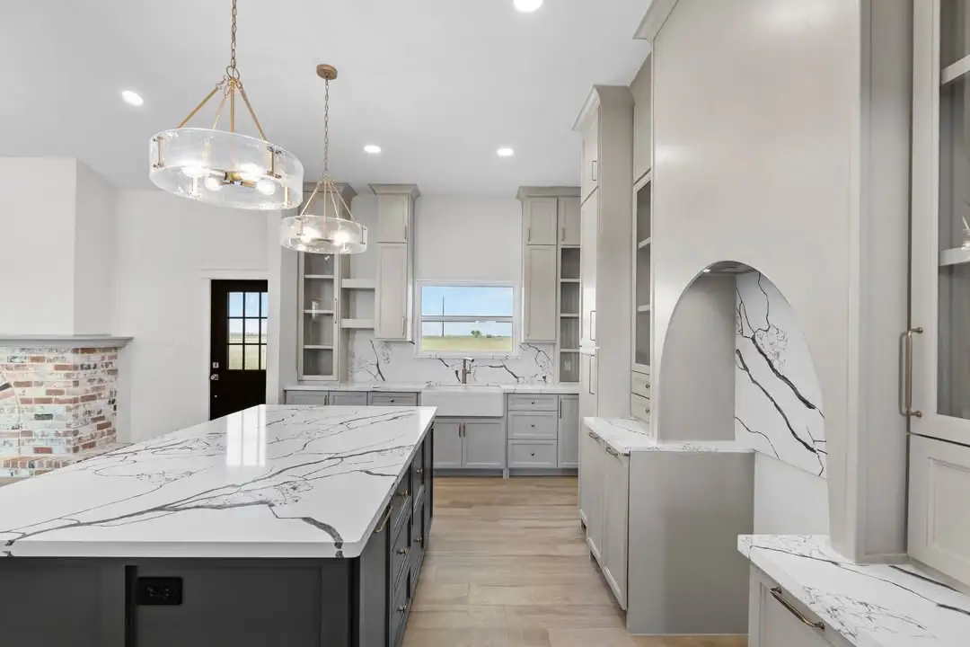 Island in veined marble with a brick backsplash and brass pendants