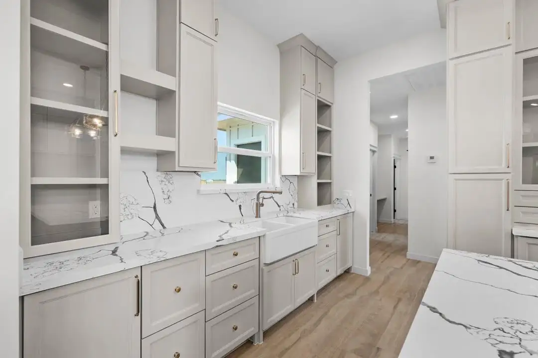 Kitchen wall with the sink under the window, white uppers and the pantry pass-through