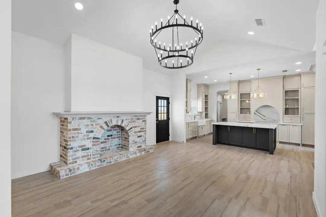 Living room with a whitewashed brick fireplace and an iron chandelier under the vault