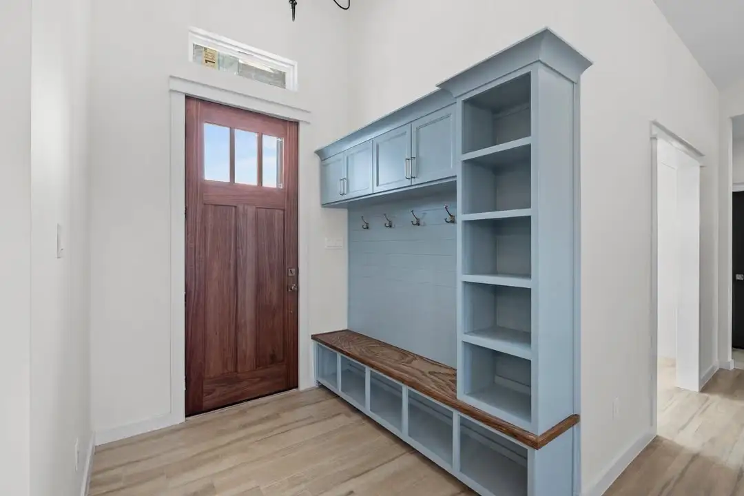 Mudroom with a wood bench, blue lockers and the wood front door