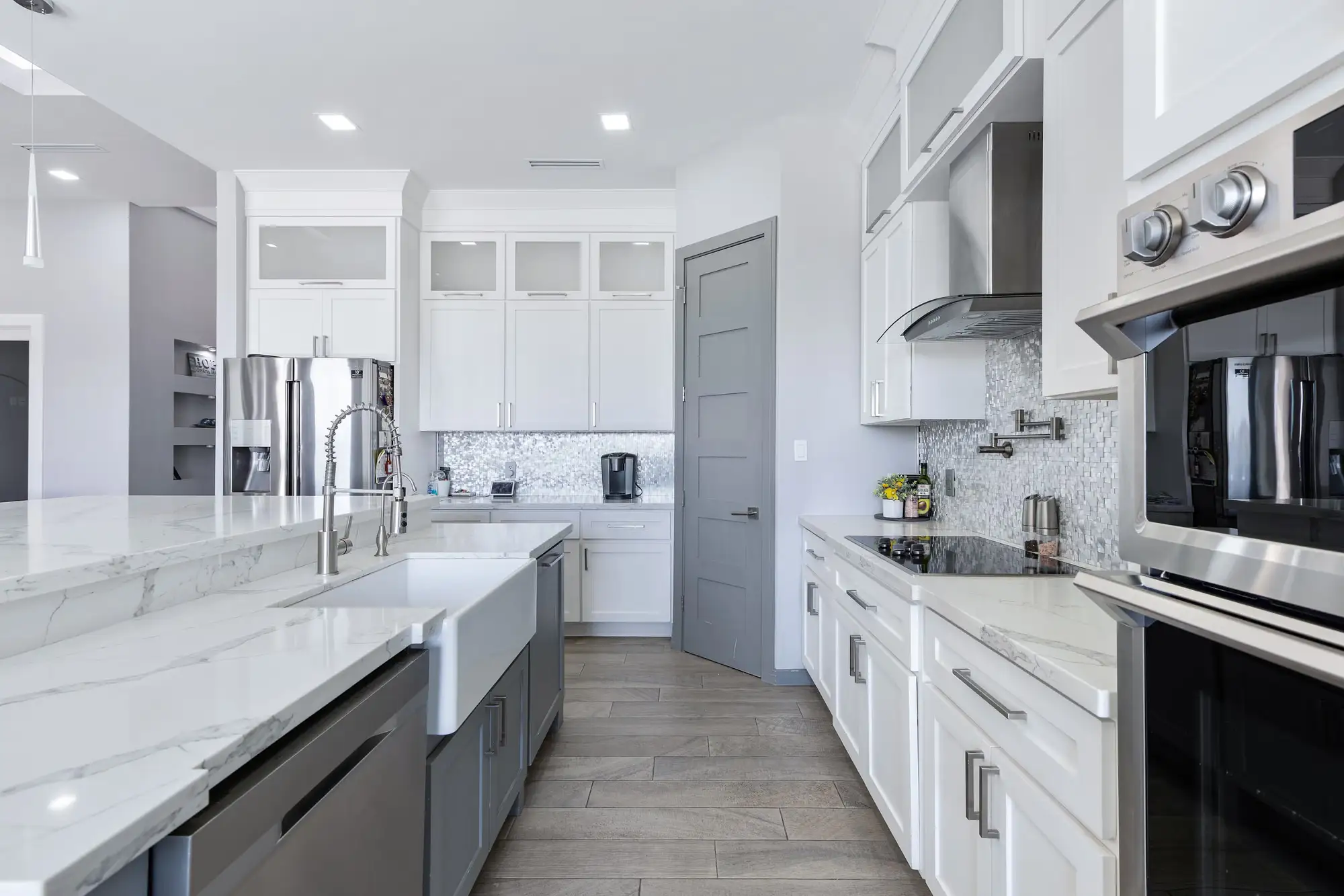 Kitchen run with a farmhouse sink, ceiling-height white cabinets and stainless appliances