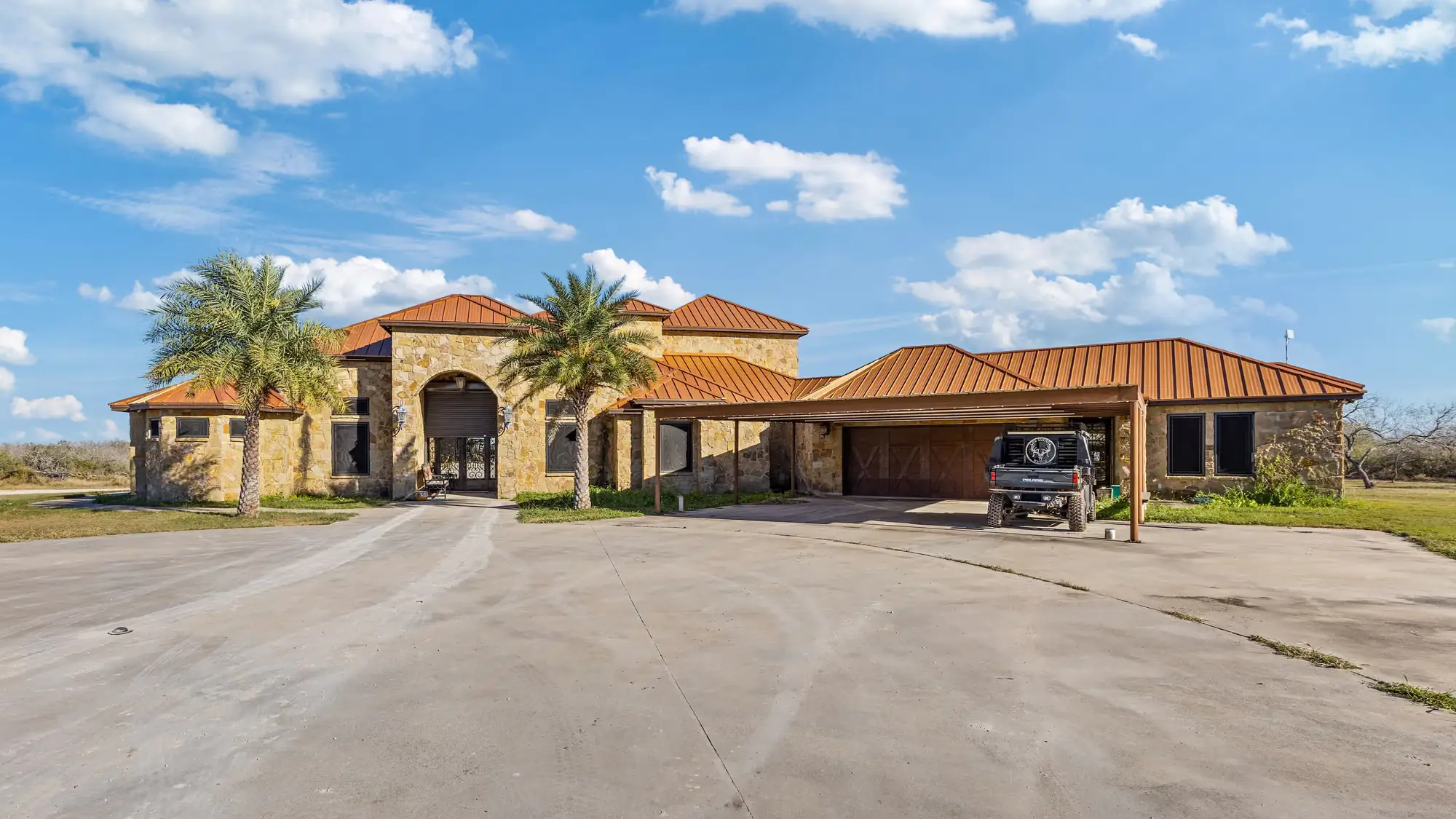 Concrete drive reaching the arched stone portico