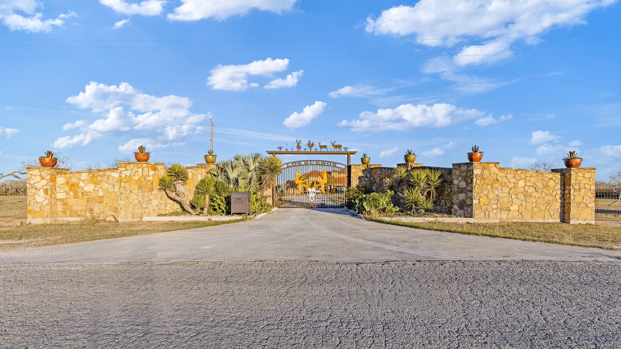 Ranch entrance with a stone wall and property gate