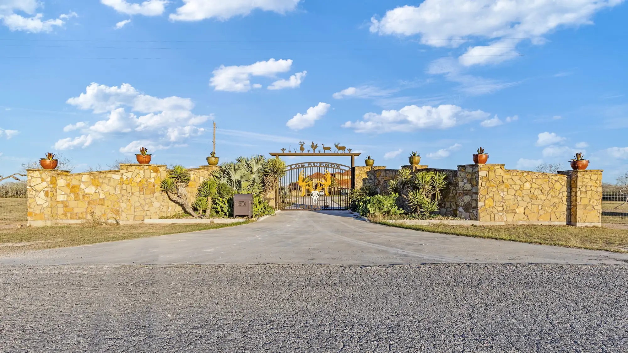 Ranch entrance with a stone wall and property gate